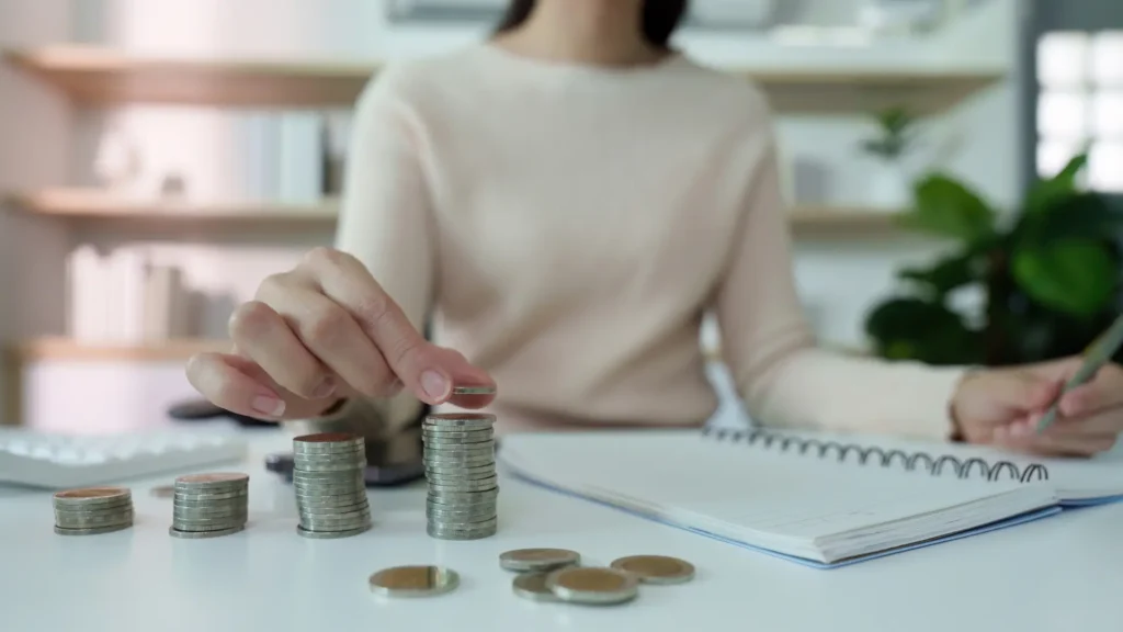 Apilando monedas y tomando nota para representar buenos hábitos financieros