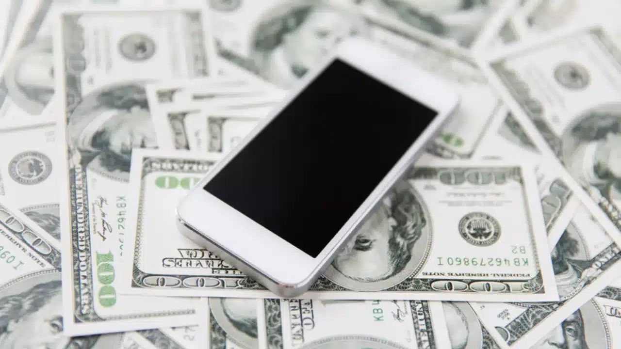 Celular sobre billetes de dolar que representa ahorrar en dolares digitales con stablecoins en Mexico