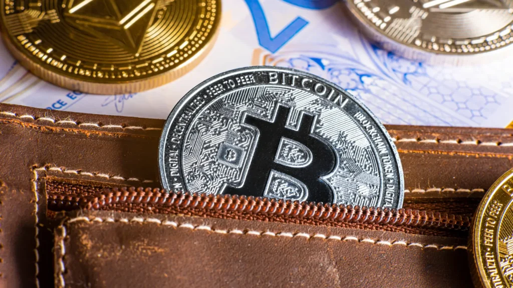Bitcoin en moneda física guardado en una cartera física común y corriente para representar una wallet cripto digital.